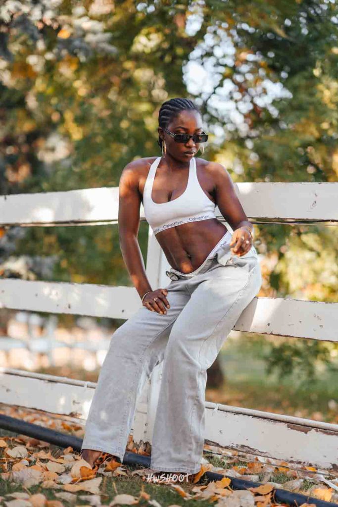 Woman leaning against a white fence during a fall photoshoot at Spruce Meadows in Calgary