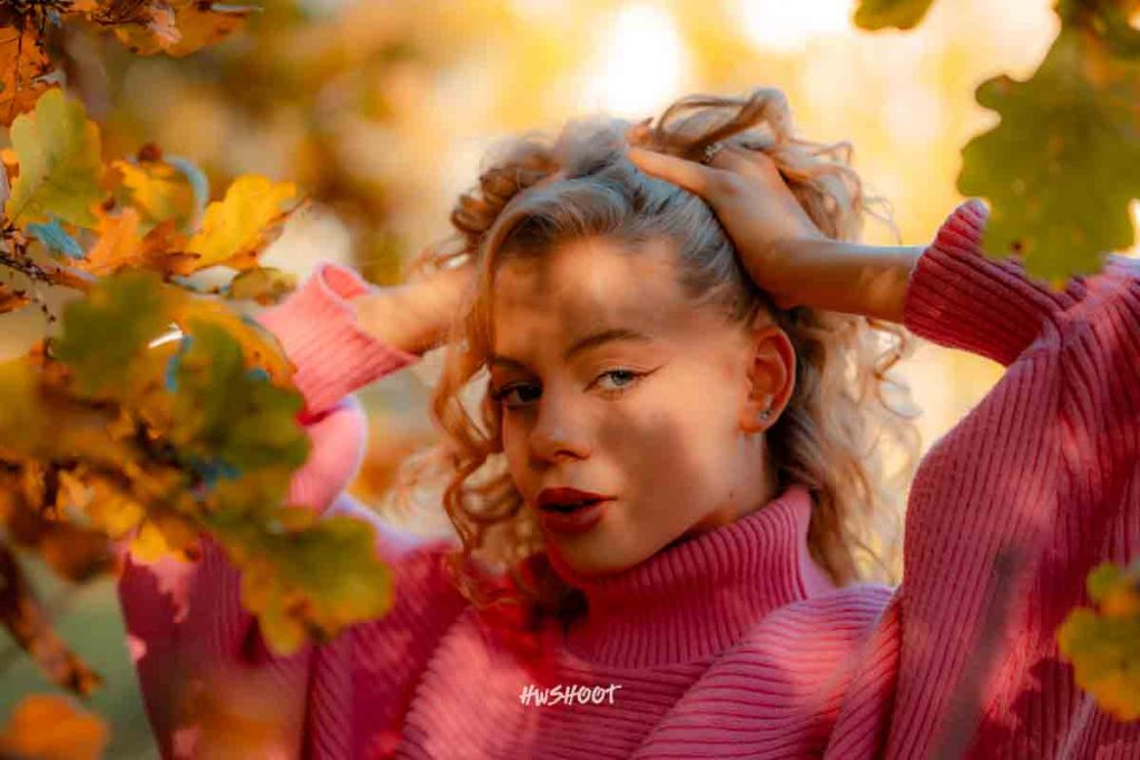 Woman in a pink sweater holding a coffee cup during a fall cafe photoshoot in Calgary