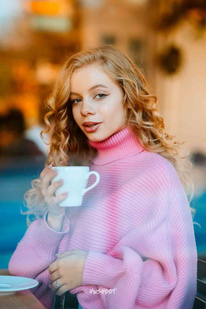Fall portrait of a woman in a pink sweater surrounded by golden autumn leaves in Calgary